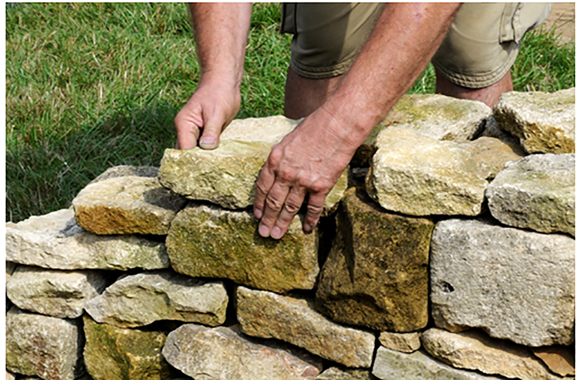 Skilled hands place rocks and building a stone wall